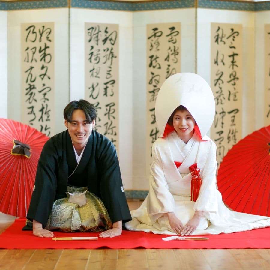 和装の新郎新婦が屏風の前で正座
