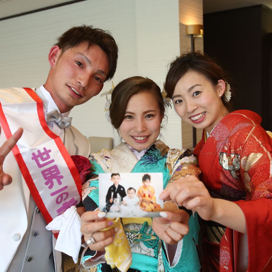 自分たちの小さい頃の写真を持った3人兄妹